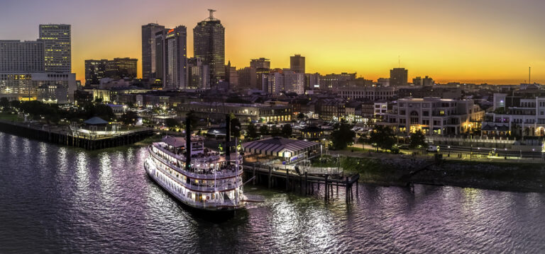 New Orleans travel guide image of a Mississippi River riverboat with the downtown skyline at sunset